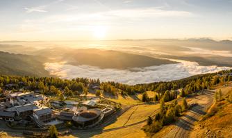 A picturesque landscape with a sunrise over the mountains. Gentle hills and fog cover the valley.