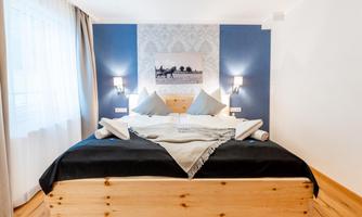 A cozy bedroom with a large bed and modern walls. The soft cushions and wooden details create an inviting atmosphere.