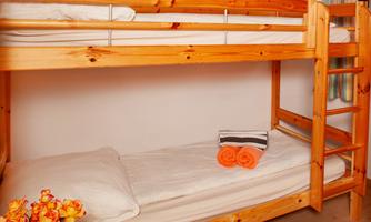 A wooden bunk bed with white bedding and colorful towels. Fresh flowers are on the floor.