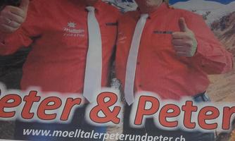 Two men in red shirts and white ties are smiling and giving thumbs up. In the background, mountains can be seen along with the text "Die Moelltaler".