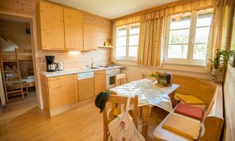 A cozy kitchen with wooden cabinets and a dining table. Large windows let in plenty of light and create an inviting atmosphere.