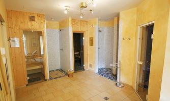 A bright spa with wooden paneling and two shower stalls. On the left is an area with a wooden bench that invites relaxation.