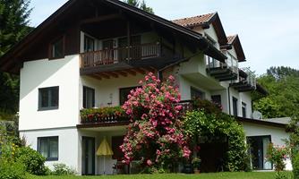 A beautiful house with a large garden and many colorful flowers. The architecture is traditional, with a balcony on the upper floor.