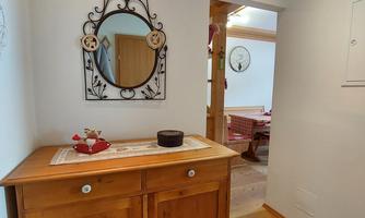 An inviting hallway with a wooden cabinet and a decorative mirror. The floor is covered with a cozy rug.