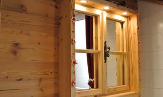 A rustic bathroom with wood paneling and a large window. The wash area is designed in a modern and elegant style.