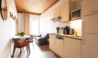 A bright kitchen with modern appliances and a small dining area. The room has a cozy seating area and plenty of natural light.