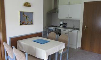 A cozy kitchen area with a table and chairs. The modern kitchen equipment is clearly visible.