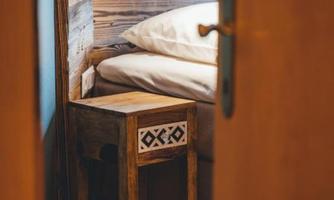 A cozy bedroom with a bed and a small wooden tray. The walls are made of wood, creating a warm atmosphere.