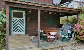 A cozy covered area with a table and chairs. The entrance is decorated with a green and white door.