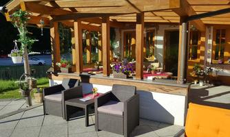 An inviting outdoor area with wooden construction and comfortable furniture. Colorful flowers and table decorations create a cozy atmosphere.