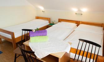 A cozy room with three beds and a table. Fresh towels are ready, and the light is pleasant.