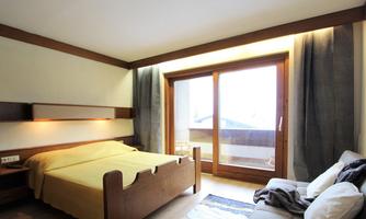 A cozy bedroom with a double bed and a large window. The warm colors and wooden details create an inviting atmosphere.