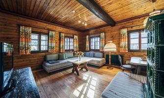 A cozy living space with wooden paneling and a large window. There are comfortable seating options and a table in a warm, inviting atmosphere.