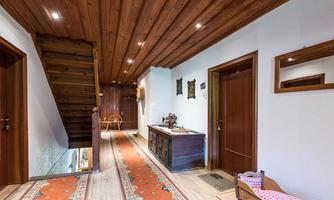 An inviting hallway with a wooden ceiling and carpet. Pictures are on the wall and the staircase leads upstairs.