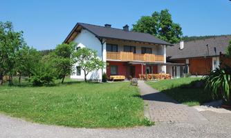 A modern house with a large garden and a terrace. The blue sky and the green surroundings create an inviting atmosphere.