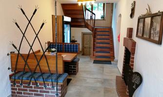 An inviting hallway with a cozy sitting area and wooden staircase. The walls are adorned with decorative elements and pictures.