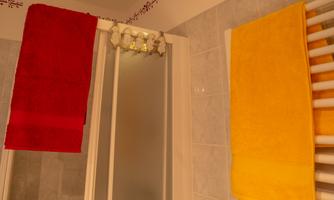 A bathroom with a red and a yellow towel hanging on a radiator. In the background, a shower glass wall is visible.