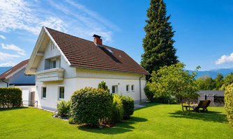 A beautiful house with a well-maintained garden and plenty of greenery. The sun is shining and the sky is clear.