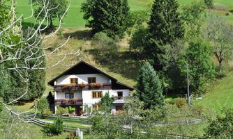 A charming house surrounded by green hills and trees. The tranquil landscape conveys a sense of idyll and relaxation.