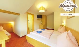 A cozy room with two beds and a modern television. The warm lighting and wooden details create an inviting atmosphere.