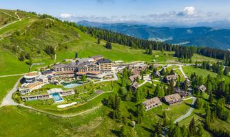 A picturesque hotel in the mountains surrounded by green meadows and forests. The pool area and the surrounding chalets invite you to relax.
