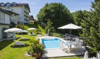 A beautiful outdoor area with a swimming pool and sun loungers. Surrounded by green spaces and parasols, the place offers a relaxed atmosphere.