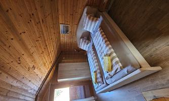 A cozy bedroom with a wooden ceiling and two single beds. Soft lighting and a wooden dresser create a relaxed atmosphere.