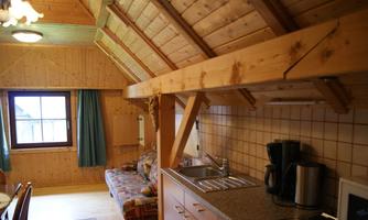 A cozy kitchen with wooden paneling and a small dining area. The windows allow for plenty of light and offer a view outside.
