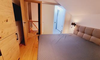 A modern bedroom with a large bed and wooden cabinets. The walls are bright and the lighting is pleasant.