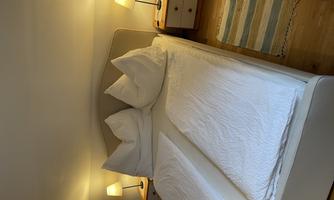 A cozy bedroom with a large bed and two nightstands. The warm lights create an inviting atmosphere.