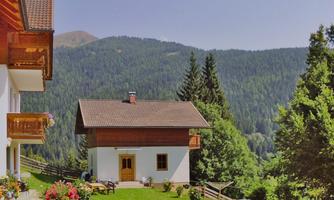 A lovely house in the mountains with a garden and colorful flowers. The view of the green forests and the mountains in the background is awe-inspiring.