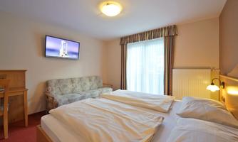 A cozy room with two beds, a television, and a large window. There is also a seating area with a sofa and a table.