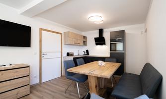 A modern kitchen with wood and gray tones. The dining area is simply and invitingly designed.