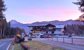 A cozy inn in the mountains at sunrise. Mountain landscape in the background with soft colors in the sky.