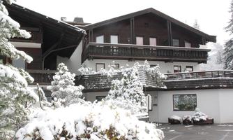 A snow-covered chalet in winter with a traditional wooden design. Surrounded by snow-covered trees and a calm atmosphere.
