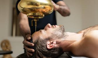A relaxing wellness treatment. A man is receiving an oil treatment while lying on a massage table.