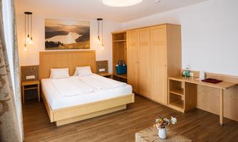 A modern bedroom with a double bed and wooden shelves. Bright walls and a pleasant atmosphere create coziness.