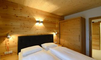 A cozy bedroom with wood paneling and a double bed. The atmosphere is warm and inviting.