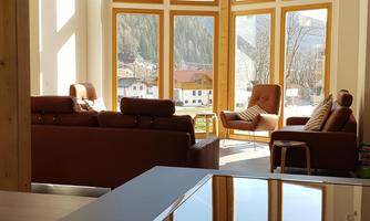 A bright living atmosphere with large windows and a view of the mountains. The modernly furnished kitchen is visible in the foreground.