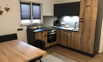Modern kitchen design with wooden and dark elements. A dining table with chairs complements the space.