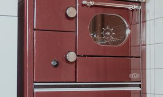A classic red kitchen stove stands in a corner. The surroundings consist of white tiled walls.