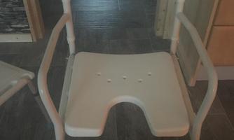 A practical chair made of plastic with armrests and a breathable seat. It is in a light color tone and is well suited for wet environments.