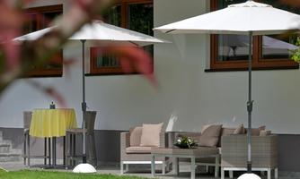 A cozy seating area outdoors with white umbrellas. The grass is green and there is a small table with a yellow tablecloth.