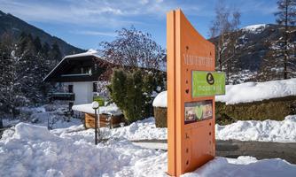 An inviting building in a snowy landscape. An orange sign points to the accommodation.