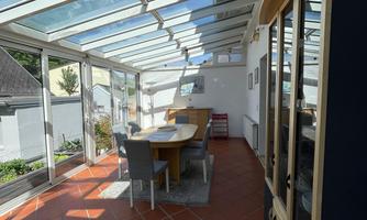 Conservatory with dining table in the middle. The floor is tiled with terracotta tiles.