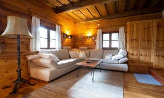 A cozy living room with wooden paneling. A large, bright couch and a table create an inviting atmosphere.