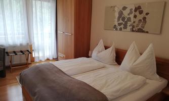 A cozy bedroom with a large double bed and bright curtains. The room has hardwood floors and modern furniture.