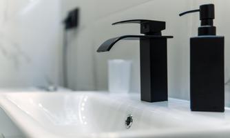 A modern sink with a black faucet and soap dispenser. The space feels elegant and minimalist.