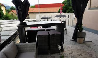 A stylish outdoor area with a gazebo, comfortable furniture, and a small plant on the table. The space is cozy and inviting, perfect for relaxing hours outside.