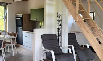 A cozy living kitchen with wood paneling and modern furniture. In the foreground are two comfortable lounge chairs.